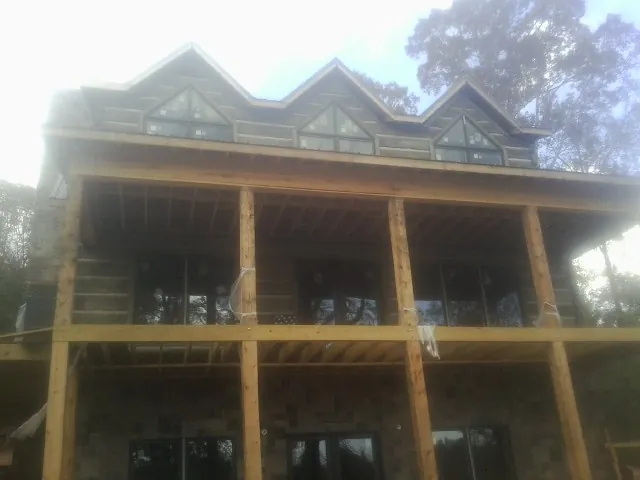 Dormers and porch framing on a large log home under construction — Roof Coating work by our crew in New York Mills