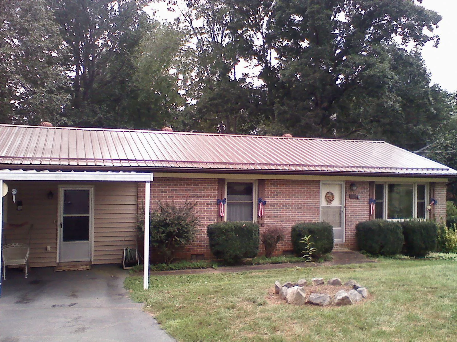 Bronze metal roof and carport on a brick ranch home — Roof Repair work by our crew in New York Mills