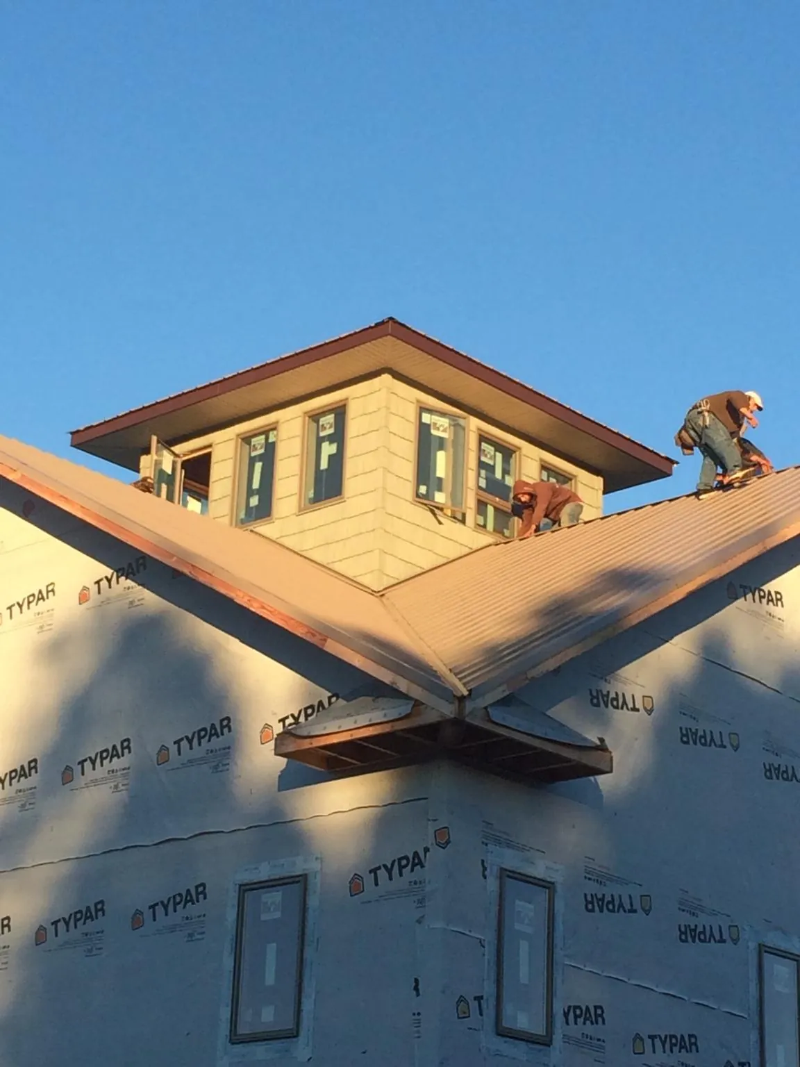 Roofers working around a rooftop cupola on a new metal roof at sunset — Roof Waterproofing in New York Mills by Roofing Brothers
